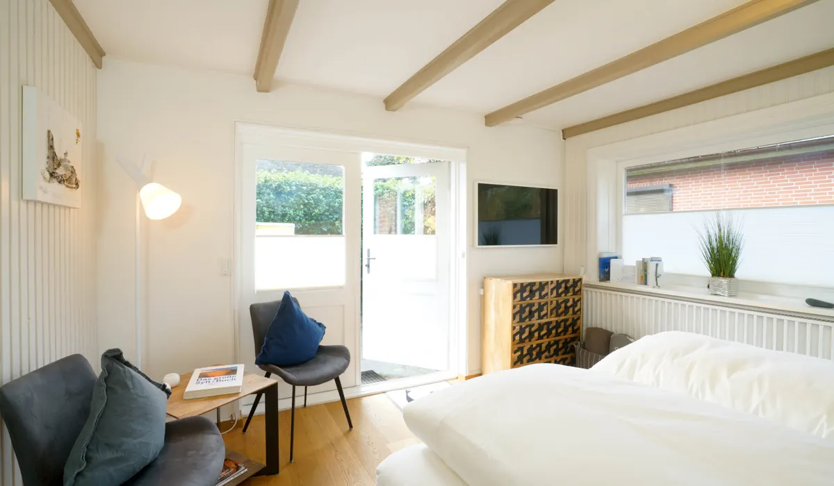 Ferienappartement mit Bett, Sessel und Tür zur Terrasse