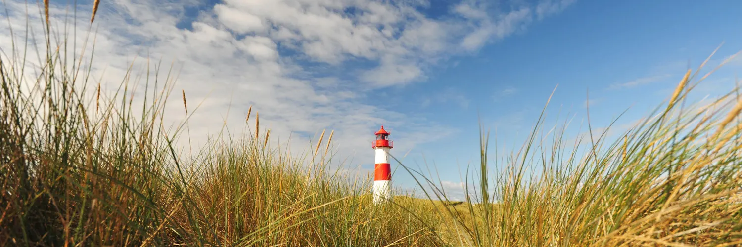 Dünen mit Strandhafer und rot-weißem Leuchtturm auf Sylt
